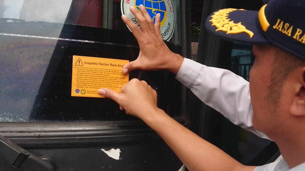 Petugas memeriksa dan memasang stiker ke bus yang sudah diperiksa. (Foto: Bramanta Pamungkas/jatimnow.com)
