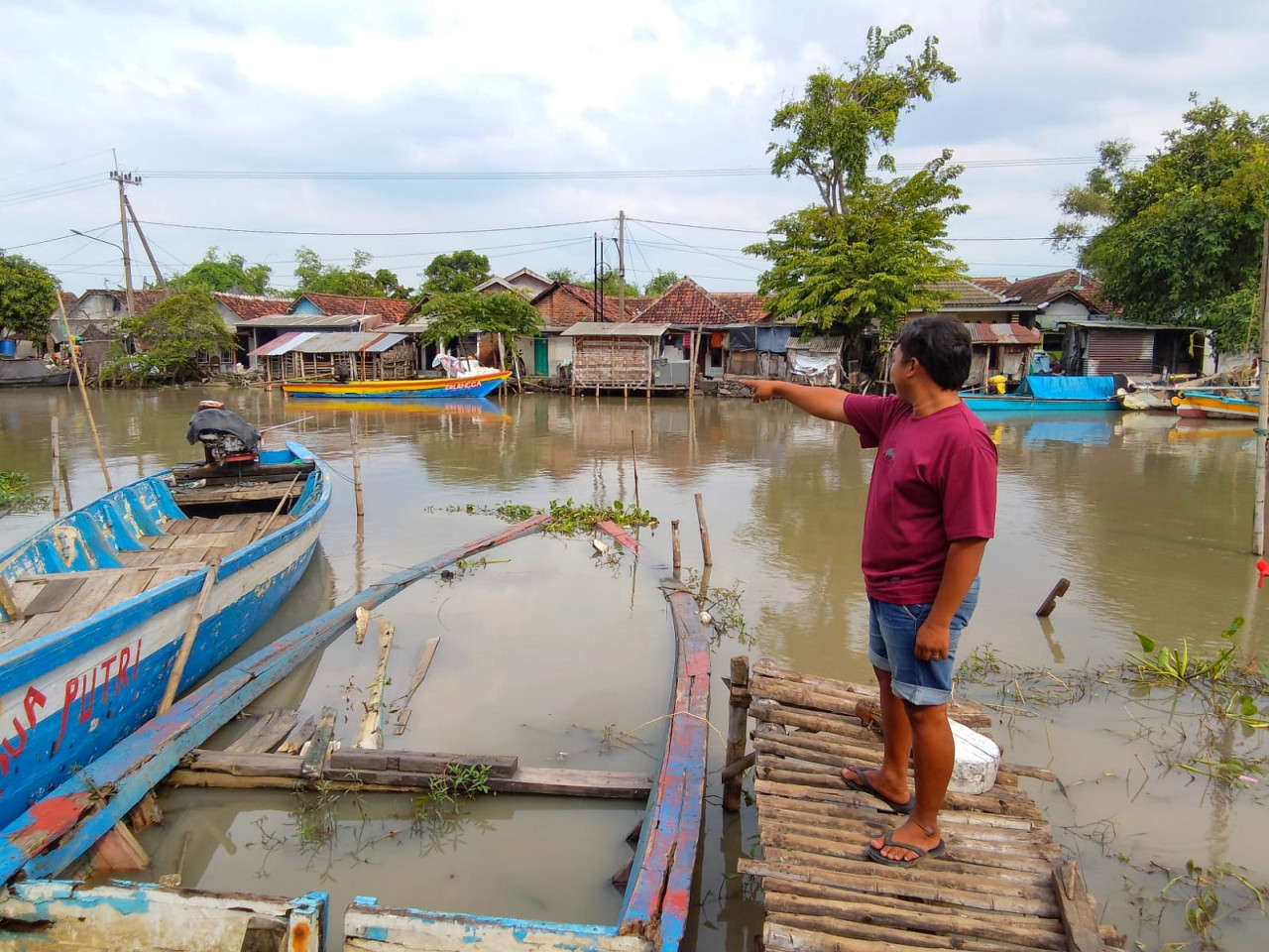 Seorang warga menunjukkan tempat buaya sering muncul di sekitar jembatan sungai Desa Kedungpeluk Candi Sidoarjo. (Foto: Ahaddiini HM/jatimnow.com)