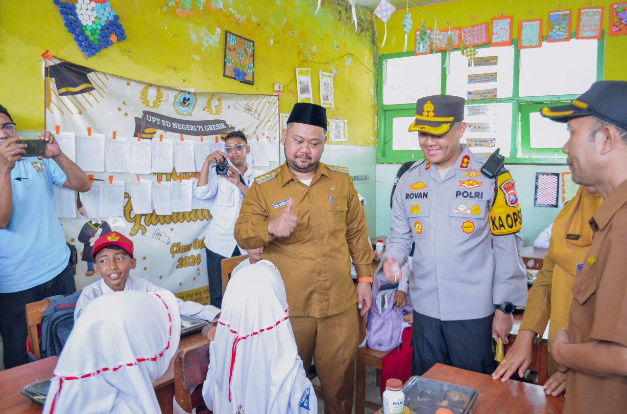Kapolres Gresik, AKBP Rovan Richard Mahenu, bersama Bupati Gresik, H. Fandi Akhmad Yani, saat menggelar kegiatan pembagian Makan Bergizi Gratis (MBG) di SDN 71 Gresik. (Foto: Humas Polres Gresik for jatimnow.com)