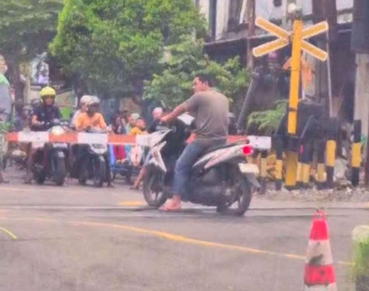 Pengendara sepeda motor menunggu kereta api melintas. (tangkapan layar)