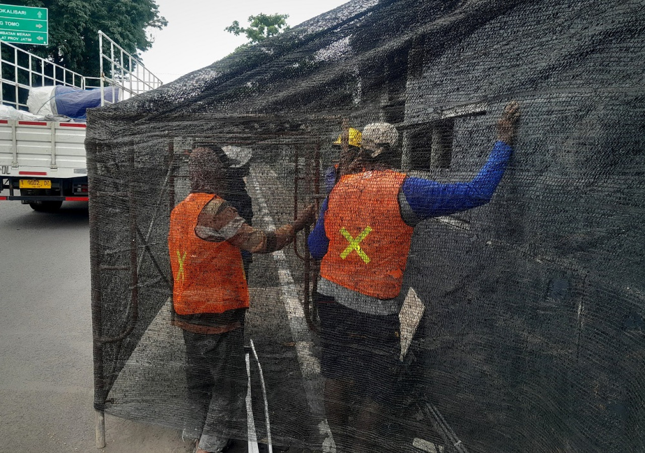 Petugas DLH sedang memperbaiki dinding Gapura Tugu Selamat Datang Perbatasan Gresik - Surabaya yang rusak. (Foto: Dok. DLH Gresik)