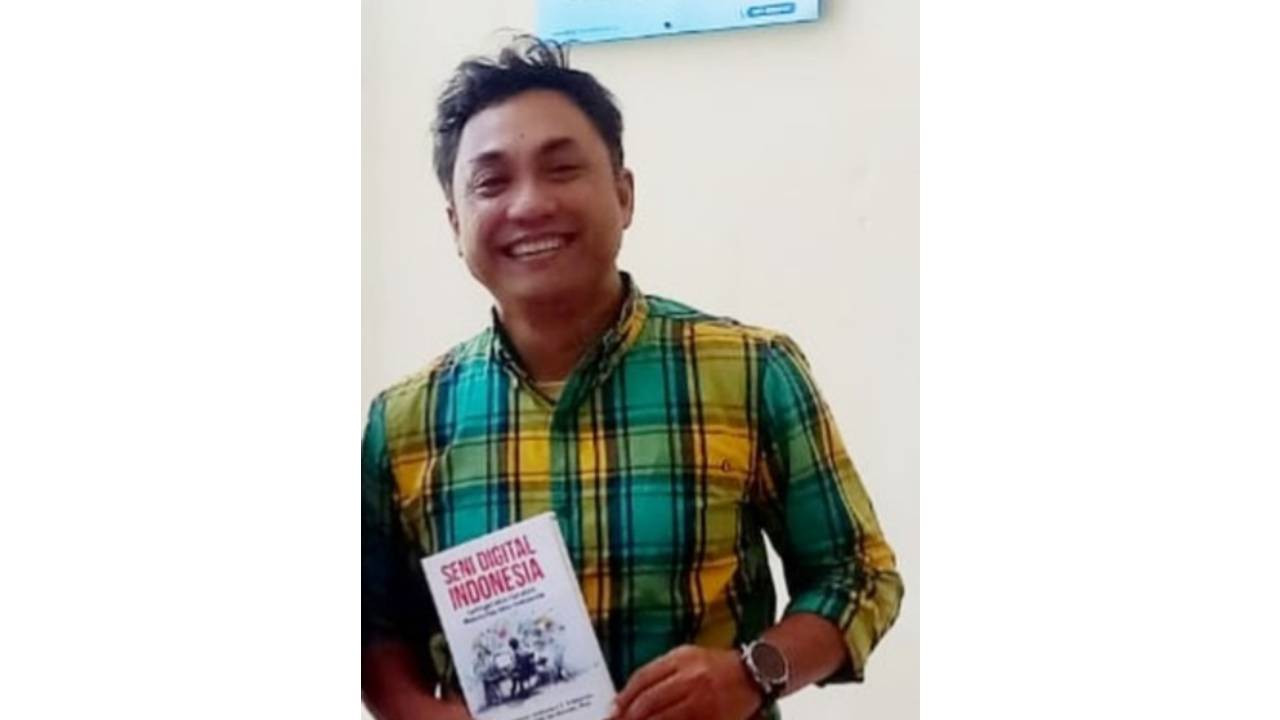 Ketua Stikosa AWS, Dr Jokhanan Kristiyono, M.Med.Kom dengan bukunya Seni Digital Indonesia, Jaringan dan Gerakan Komunitas Seni Indonesia. (Foto: Redho for jatimnow.com)