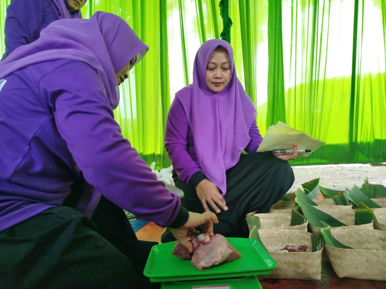 Anggota DPRD Ponorogo Fraksi PKB, Mujiatin dan Tri Suryati, membungkus daging kurban menggunakan besek di Kantor DPC PKB Ponorogo. (Foto: Ahmad Fauzani/jatimnow.com)