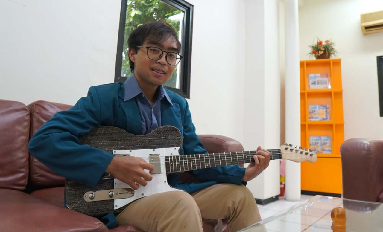Tristan Fawwaz Alvaro mejeng bersama gitar listrik ciptaanya. (Foto: Humas Ubaya)
