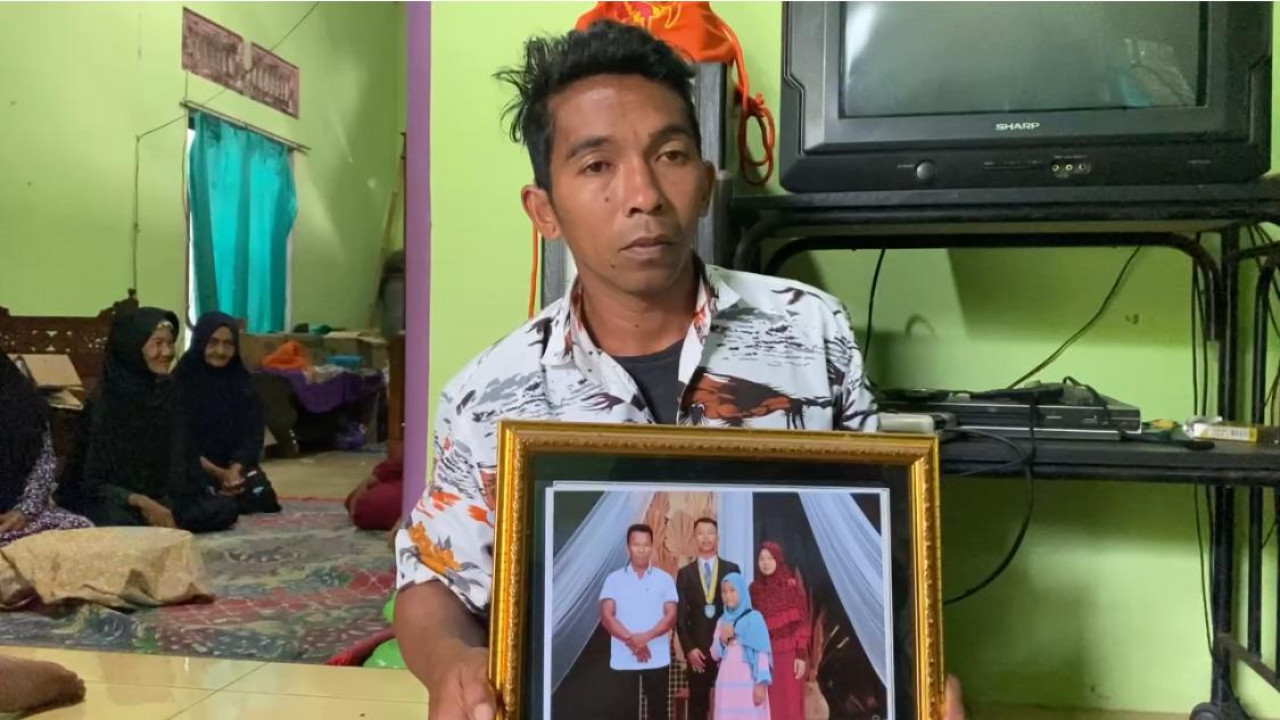 Foto : Agung menunjukkan foto ayah dan adiknya yang menjadi korban KMP Tunu Jaya Pratama (Bramanta Pamungkas/jatimnow.com)