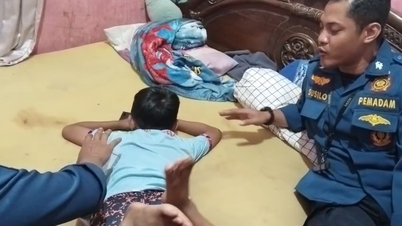 Foto: Damkar Lamongan saat mencoba menenagkan bocah ngamuk tak mau sekolah. (Damkar Lamongan/ jatimnow.com)