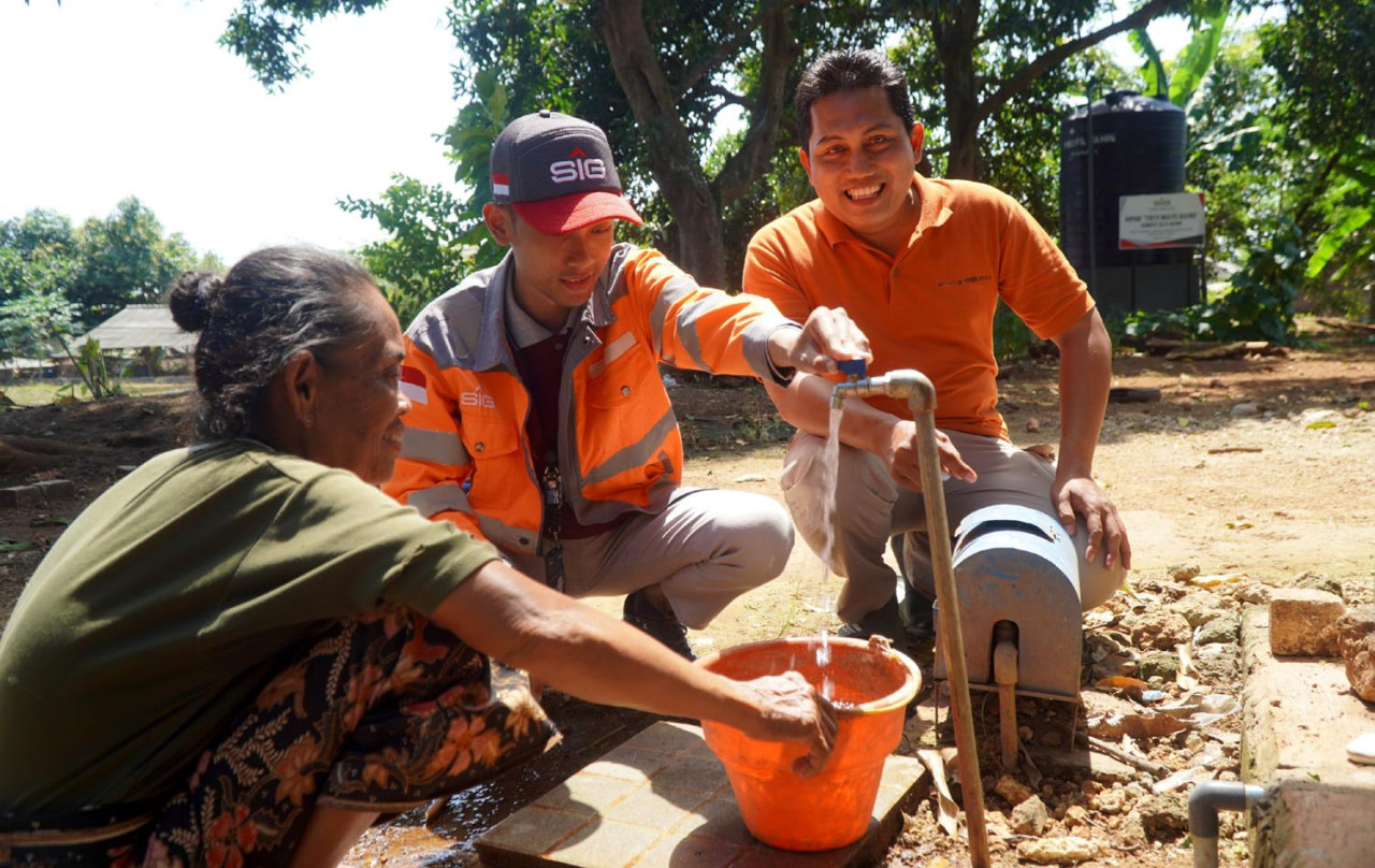 Karyawan SIG mendampingi warga Dusun Bulu, Desa Tuwiri Kulon, Kecamatan Merakurak, Kabupaten Tuban, Jawa Timur, memanfaatkan fasilitas sarana dan prasarana air bersih dari program TJSL SIG. (Foto: SIG for JatimNow.com)