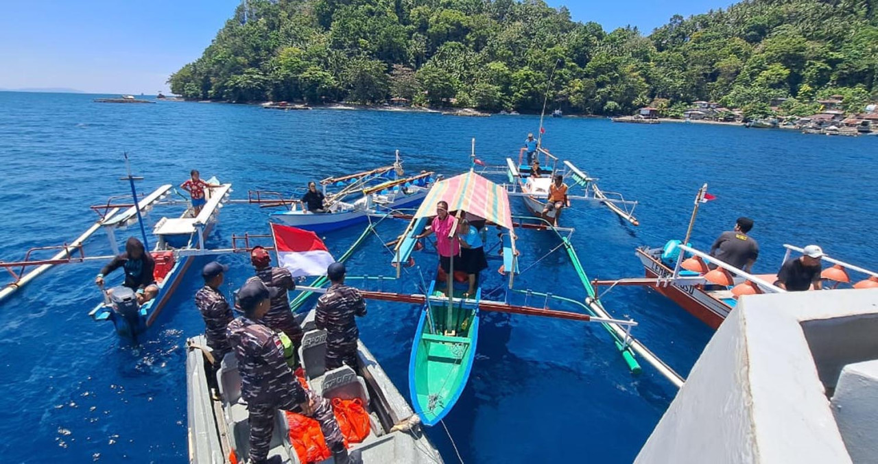 Prajurit TNI AL menyalurkan bantuan berupa sembako dan bendera merah putih secara langsung kepada para nelayan kecil yang sedang beraktivitas di laut. (Foto: Dispen for JatimNow.com)