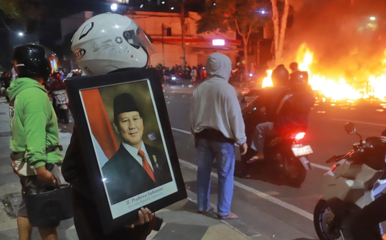Massa aksi menyelamatkan foto Presiden RI Prabowo Subianto, saat Polsek Tegalsari Surabaya dibakar, Minggu (31/8/2025) dini hari. (Foto: Surya for JatimNow.com)