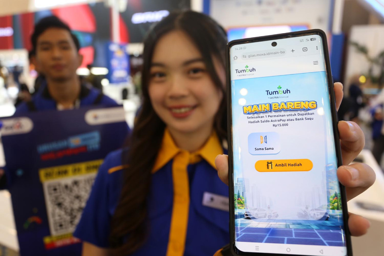 Usher menunjukkan tampilan game di booth Astra Financial dalam gelaran GAIKINDO Indonesia International Auto Show (GIIAS) Surabaya 2025. (Foto: Ali Masduki/JatimNow.com)