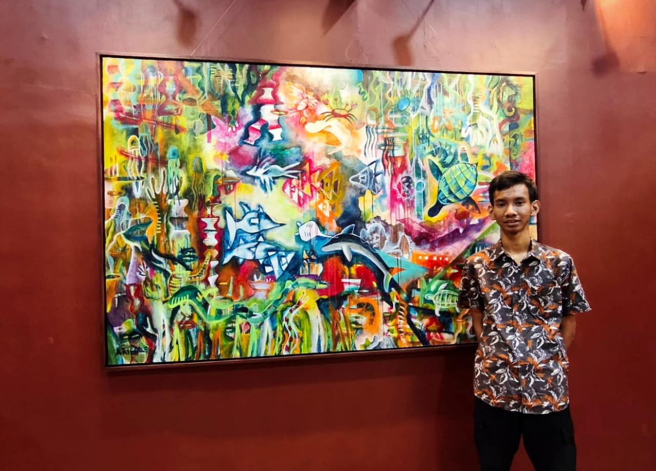 Ariel Ramadhan bersama karya lukisnya berjudul "Segara Warna", yang dipamerkan di Galeri Merah Putih Balai Pemuda Surabaya. (Dok. Pribadi)