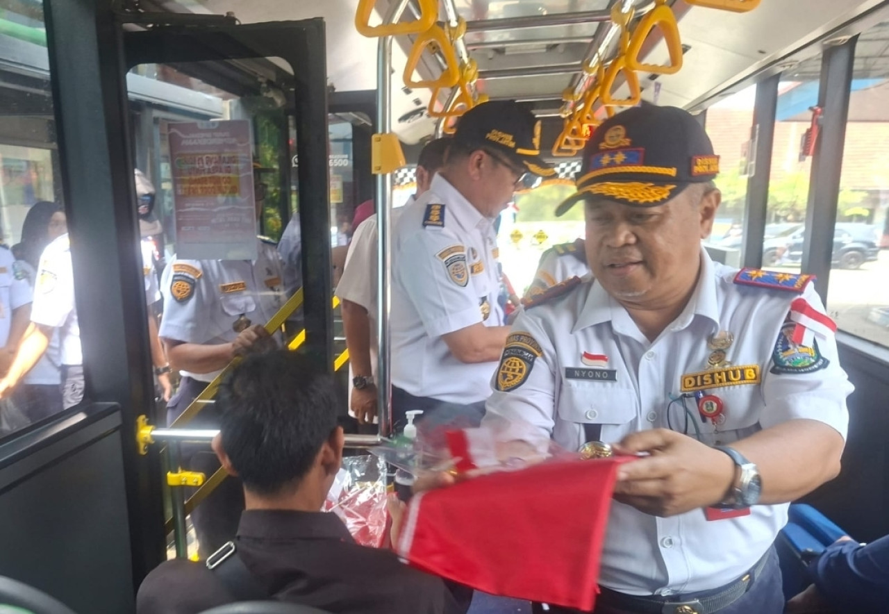 Kadishub Jatim Nyono saat membagikan bendera merah putih pada penumpang Bus Trans Jatim (foto: Dishub Jatim for jatimnow.com)