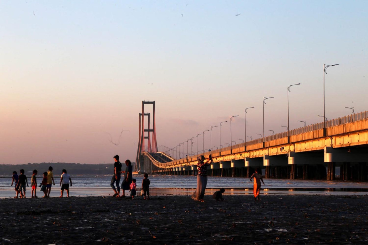 Wisatawan menikmati suasana senja ketika berwisata di Jembatan Suramadu, di Surabaya, Jawa Timur. (Foto: Ali Masduki/jatimnow.com)