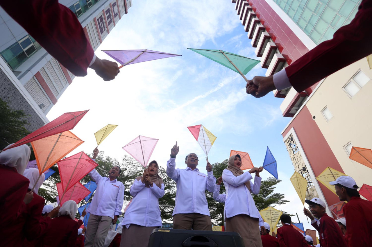 Rektor UM Surabaya, Mundakir, bersama jajaran menerbangkan layang-layang bersama ribuan mahasiswa baru dalam pembukaan Masa Orientasi (MOX) 2025. (Foto: Ali Masduki/JatimNow.com)