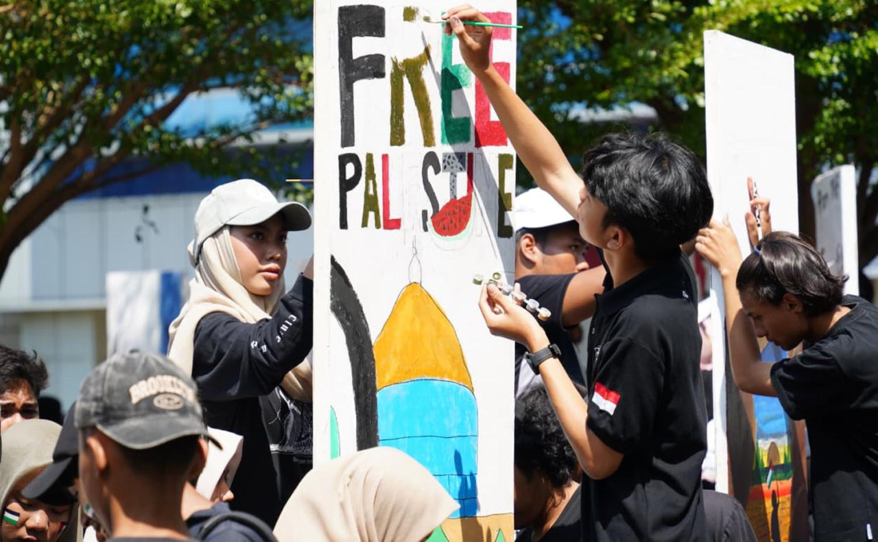Mahasiswa baru UM Surabaya menuangkan gagasan damai lewat sapuan kuas di dinding besar yang diberi nama The Wall of Peace. (Foto/Humas UM Surabaya)