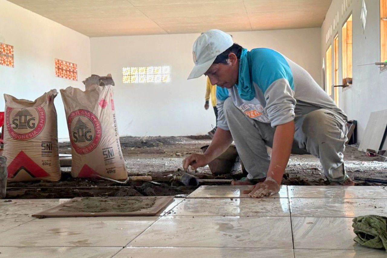 Proses pemasangan keramik lantai untuk pembangunan dan renovasi asrama santri Pondok Pesantren Minhaju Al Ihtida’ Yafi di Desa Jatisari, Kecamatan Arjasa, Kabupaten Situbondo. (Foto: SIG/jatimnow.com)