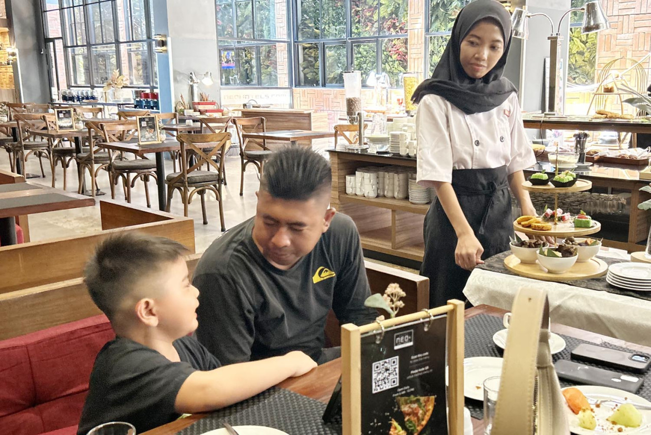 Seorang tamu bersama anaknya tampak menikmati suasana hangat sarapan pagi di restoran Hotel Neo+ Waru Sidoarjo saat peringatan World Food Day 2025. (Foto: Hotel Neo+ Waru for jatimnow.com)