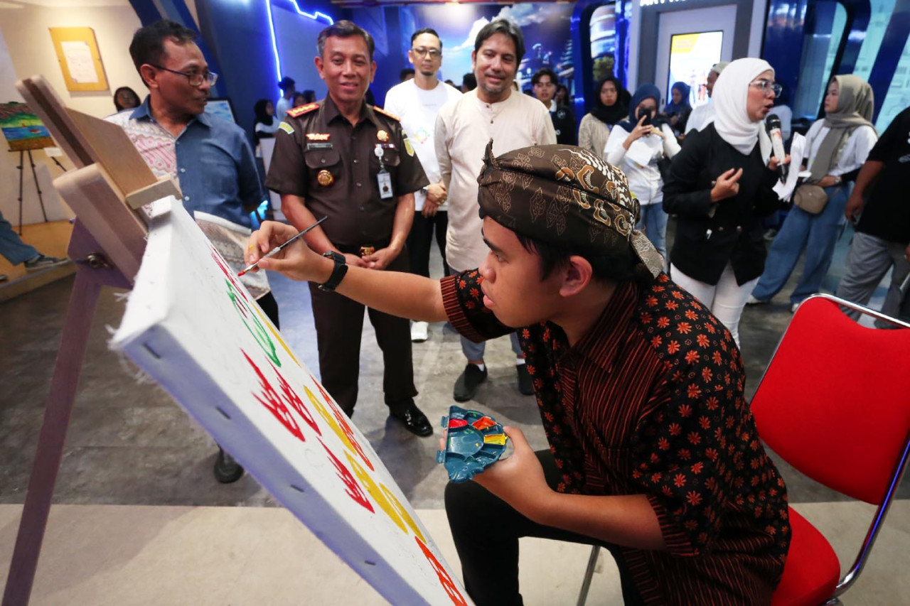 Mohammad Cahyadi dan Kepala Kejaksaan Negeri Kota Malang, Tri Joko, menyaksikan aksi melukis Dany Aryasatya Putra Yudha, seorang pelukis autis dari Kota Mojokerto. (Foto: Ali Masduki/jatimnow.com)