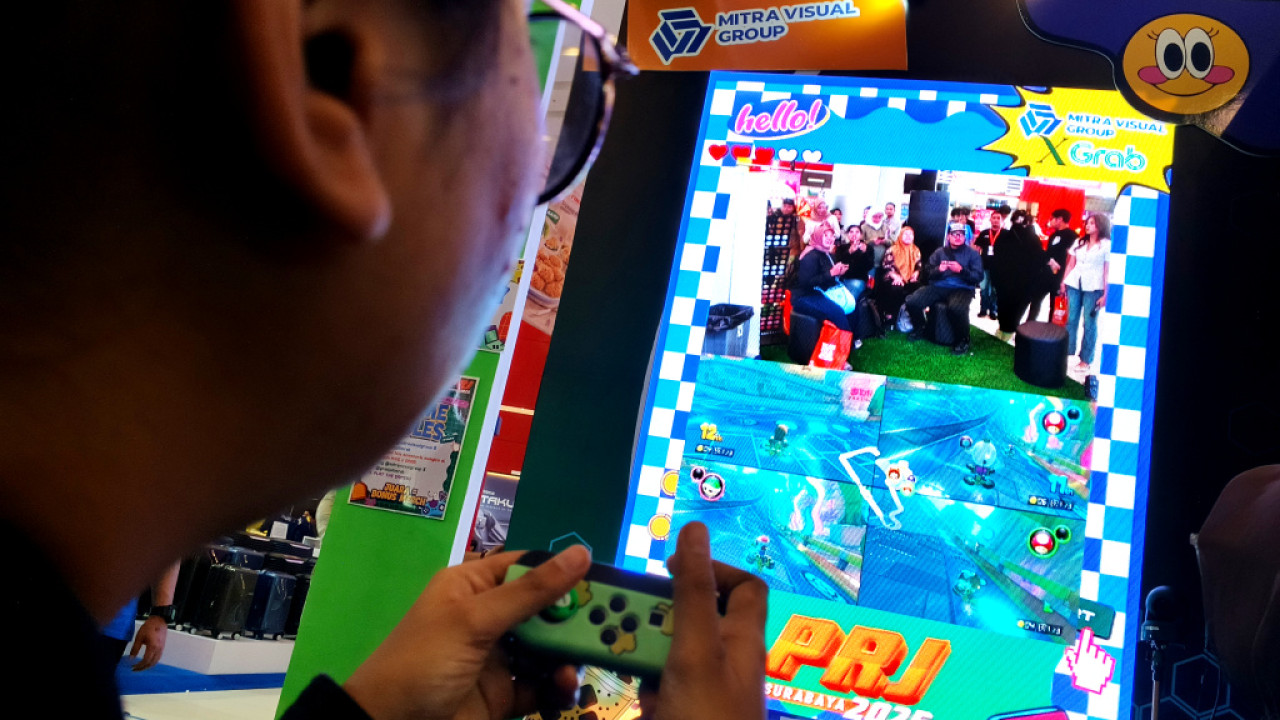 Pengunjung menjajal game interaktif yang dihadirkan Mitra Visual Group (MVG) di PRJ Surabaya 2025. (Foto: Ali Masduki/jatimnow.com).