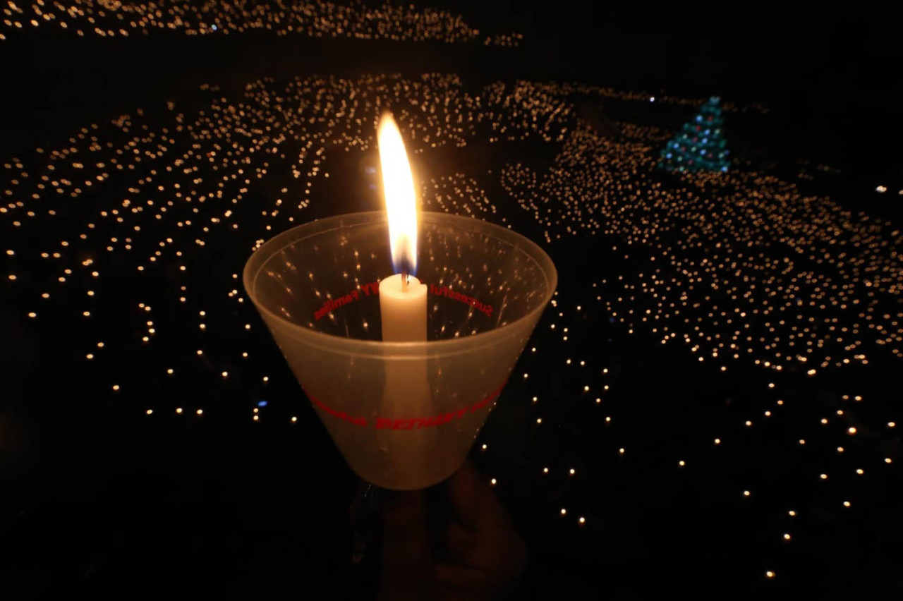 Umat Kristiani menyalakan lilin ketika mengikuti misa malam natal di Gereja Bethany Surabaya. (Foto: Ali Masduki/jatimnow.com)