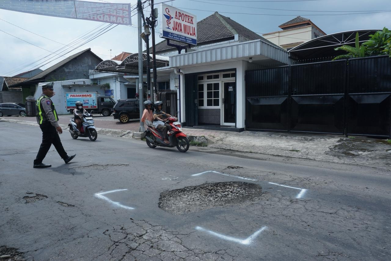 Petugas Satlantas Polres Kediri melakukan penandaan di ruas jalan berlubang. (Foto: Satlantas Polres Kediri/jatimnow.com)