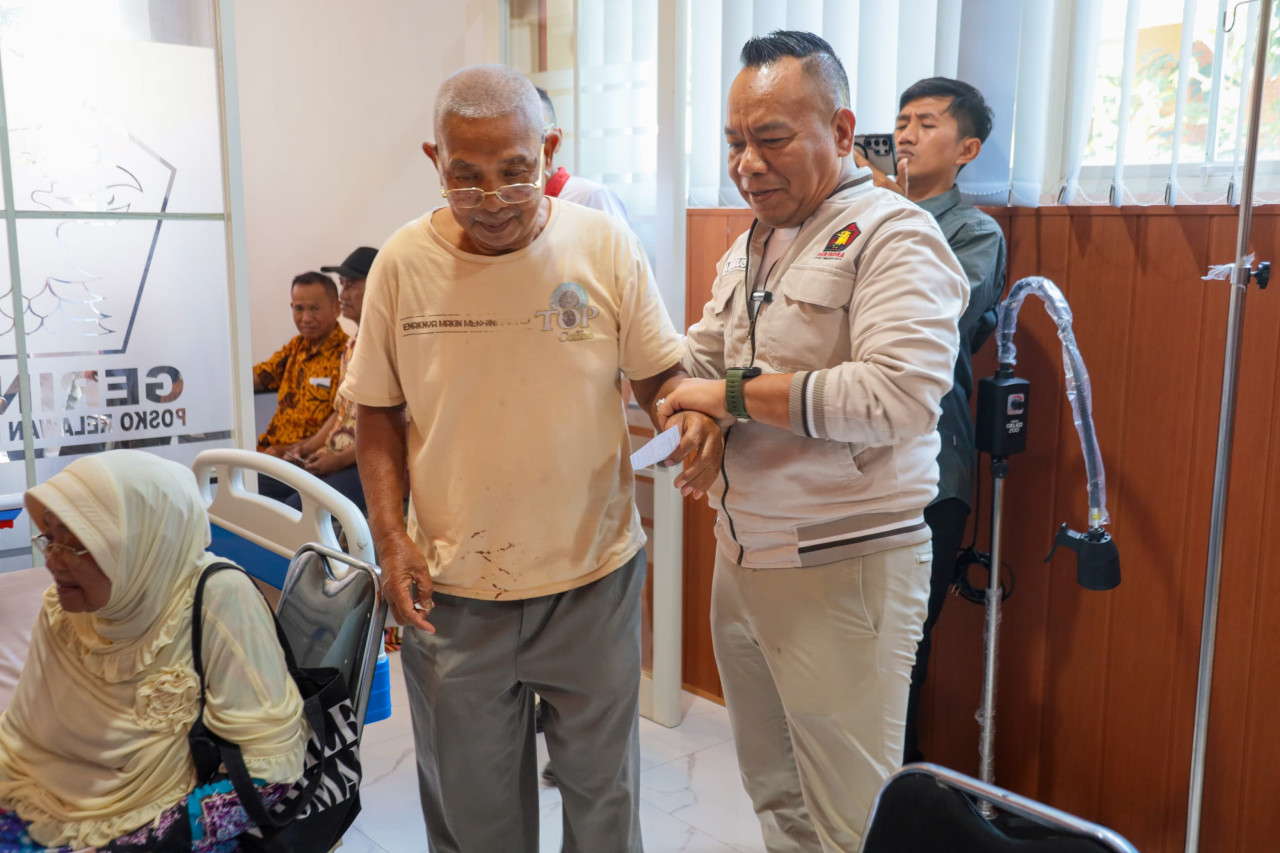 Yona Bagus (kanan) saat membantu lansia melakukan cek kesehatan gratis di posko-nya (foto: Yona for jatimnow.com)