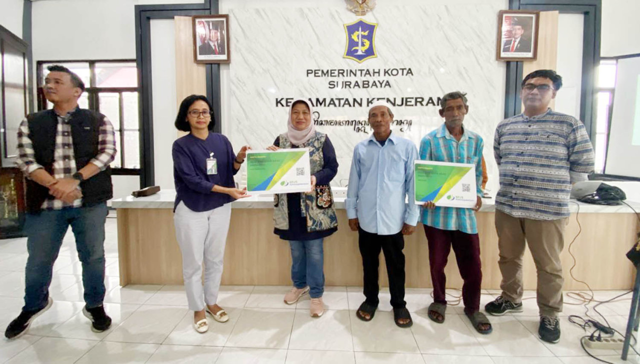 Kepala Cabang BPJS Ketenagakerjaan, Theresia Wahyu Dianti, menyerahkan secara simbolis kartu kepesertaan nelayan dan petani. (Foto: Ali Masduki/jatimnow.com)