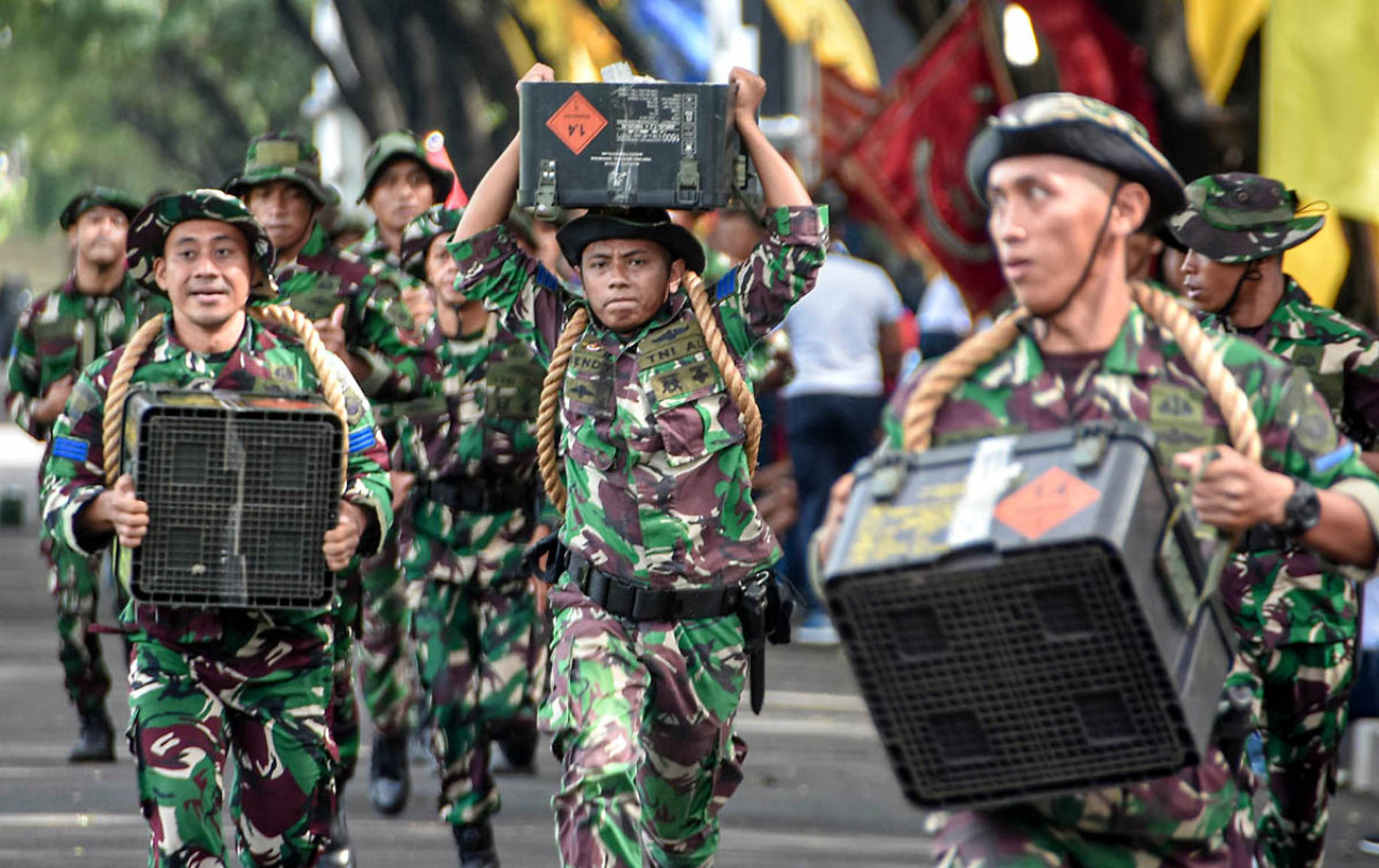 Prajurit Brigif 2 Marinir membawa dua kotak amunisi ketika beradu cepat dalam Lomba Lari Estafet Militer yang ekstrem, Jumat (13/2/2026). (Foto: Ainul Yakin for JatimNow.com)