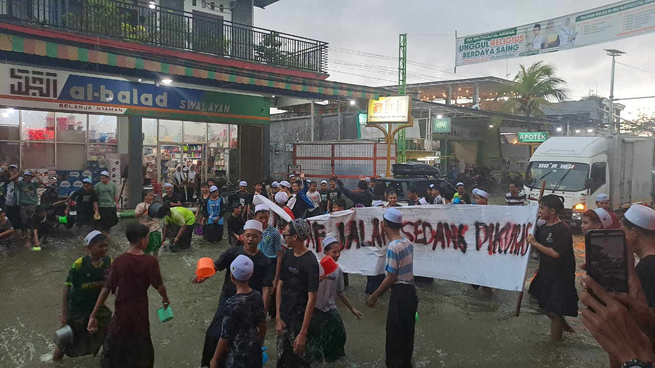 Santri Pondok Pesantren Matholi’ul Anwar Simo, Desa Sungelebak, Kecamatan Karanggeneng, Lamongan saat menguras genangan banjir di depan Ponpes (foto:Adyad Ammy Iffansah/jatimnow.com)