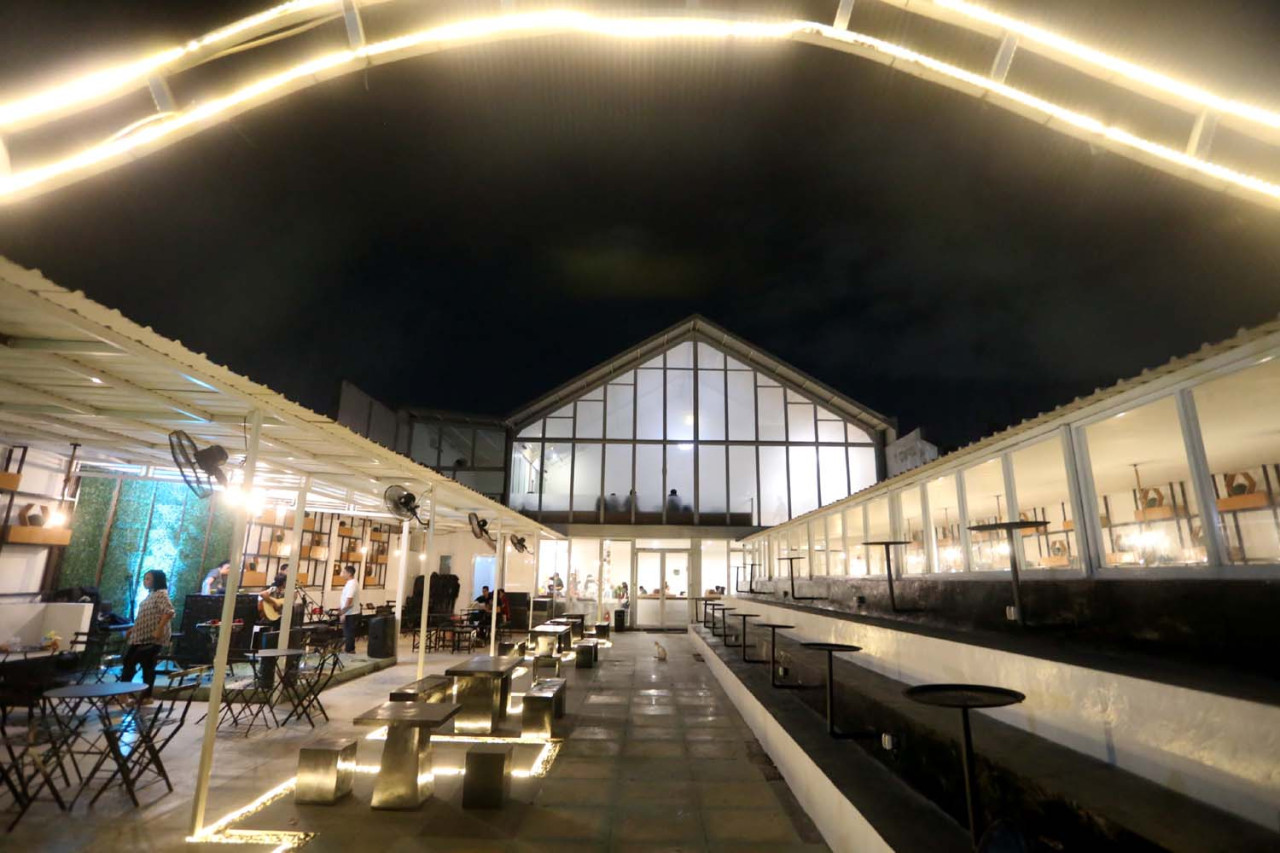 Suasana malam di Hanaka Social Space menghadirkan perpaduan ruang terbuka, live music, dan area kerja santai, menciptakan pengalaman nongkrong yang membuat pengunjung betah berlama-lama. (Foto: Ali Masduki/jatimnow.com)