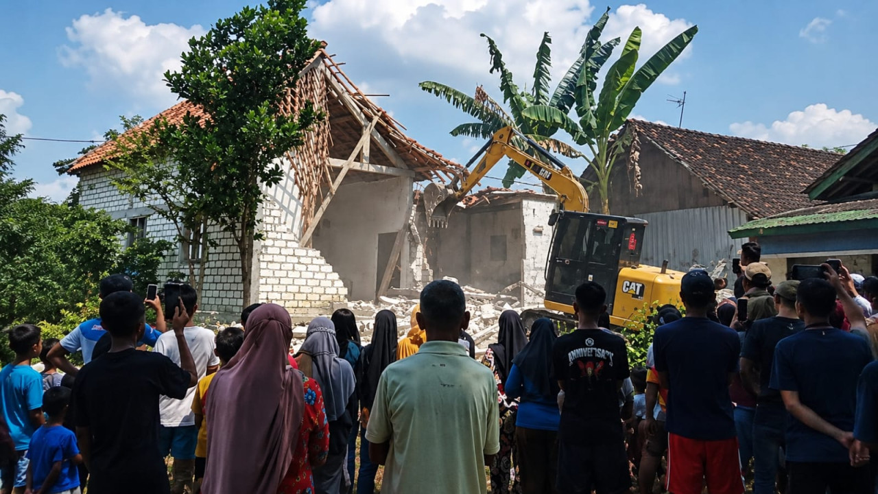 Proses Alat berat merobohkan bangunan rumah jadi tontonan warga (foto: Munir for jatimnow.com)