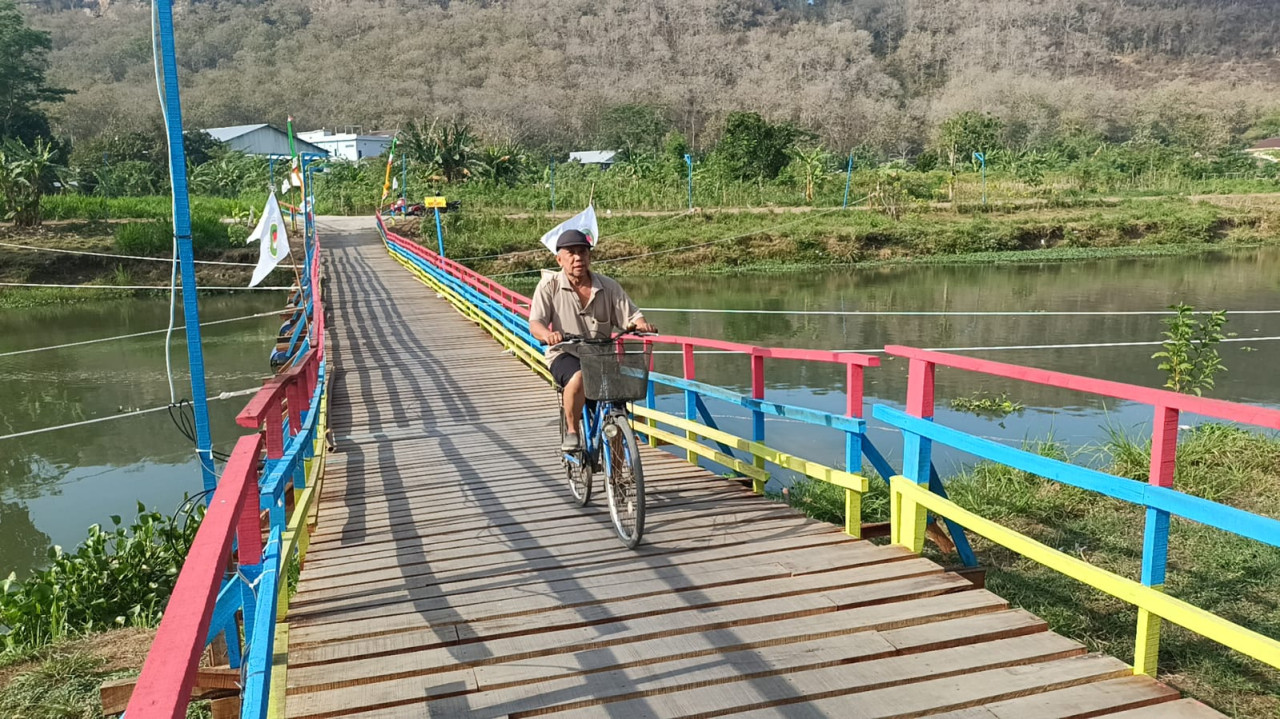 Warga Tulungagung menaiki sepeda di jembatan apung. (Foto: Bramanta/jatimnow.com)