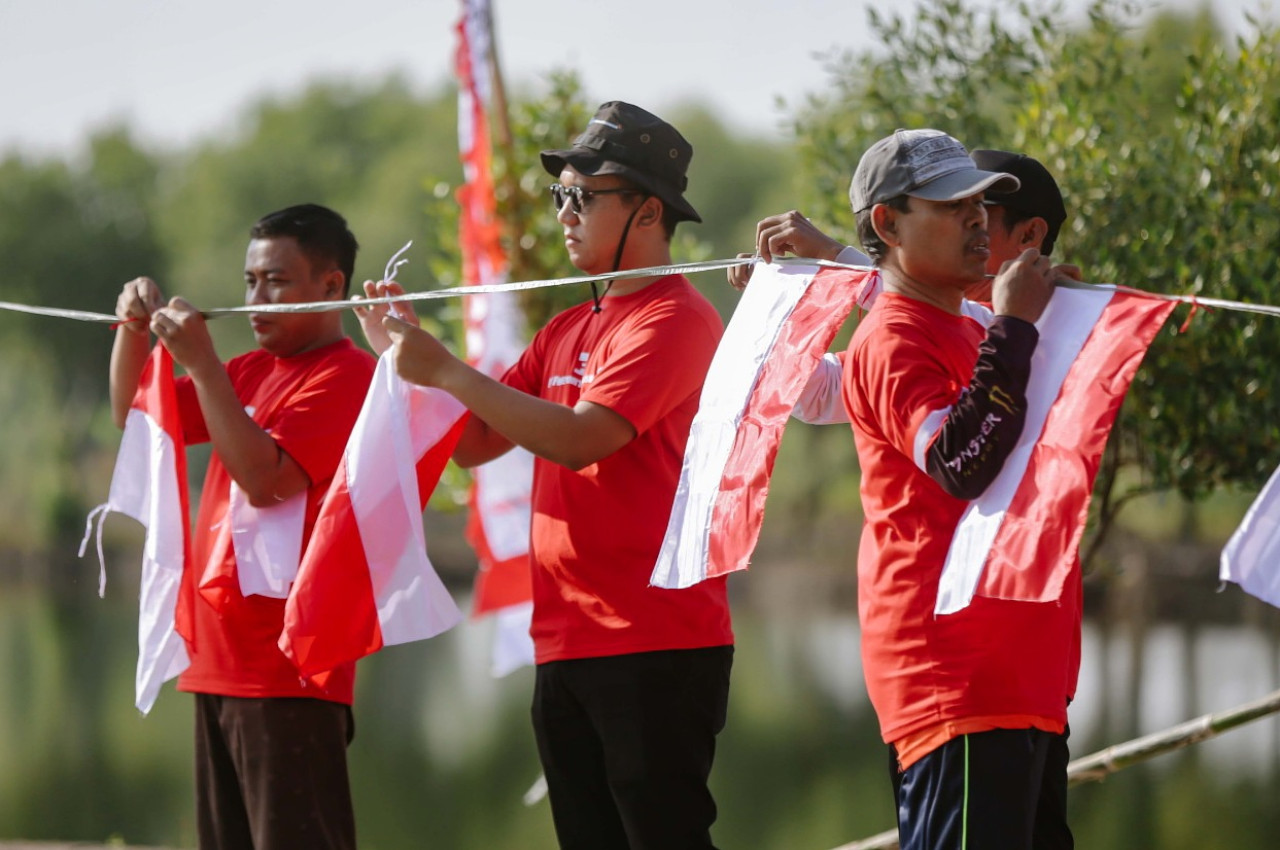 Warga Desa Banyuwangi dan karyawan PT Freeport Indonesia (PTFI) memasang bendera Merah Putih sebagai bagian dari kegiatan Gotong Royong Kemerdekaan di Desa Banyuwangi, Manyar, Gresik. (Foto: PTFI for jatimnow com)