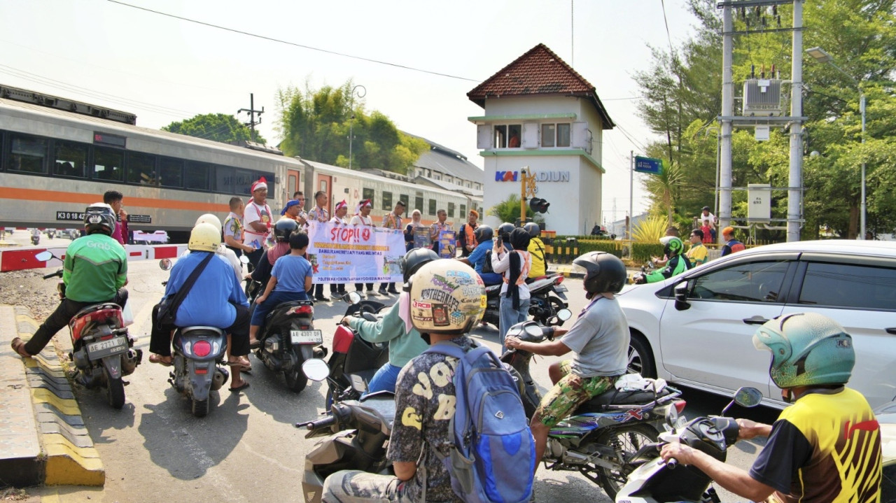 Daop 7 Madiun gandeng Railfans Pecel +63 Madiun dan siswa dari Politeknik Perkeretaapian Indonesia (PPI) Madiun sosialisasikan keselamatan dan keamanan perjalanan kereta api di perlintasan sebidang (JPL). (Foto: Daop 7 Madiun/jatimnow.com)