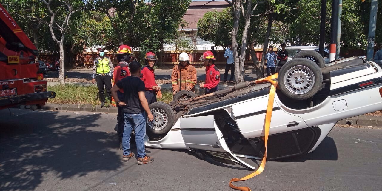 Petugas berupaya mengevakuasi mobil yang terbalik