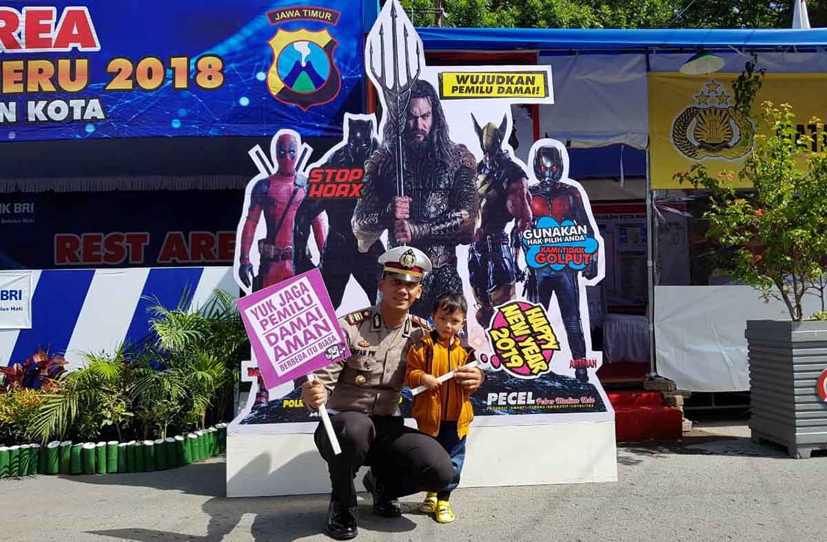Seorang anak meminta foto di depan replika Aquaman dan superhero di Pos Pengamanan Alun-Alun Madiun