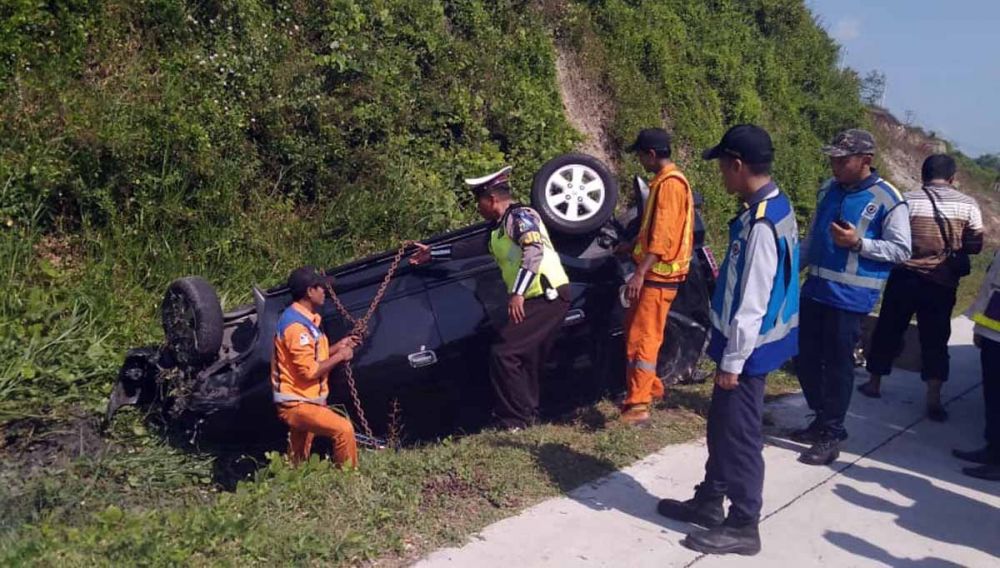 Petugas mengevakuasi mobil Avanza yang terguling di Tol Nganjuk-Madiun