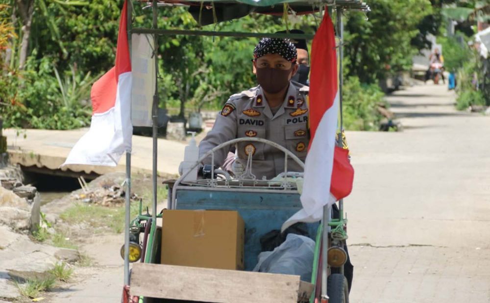 Wakapolres Mojokerto Kompol David Triyo Prasojo  (pakai blangkon) mengendarai bentor saat bagikan sembako ke warga terdampak Covid-19