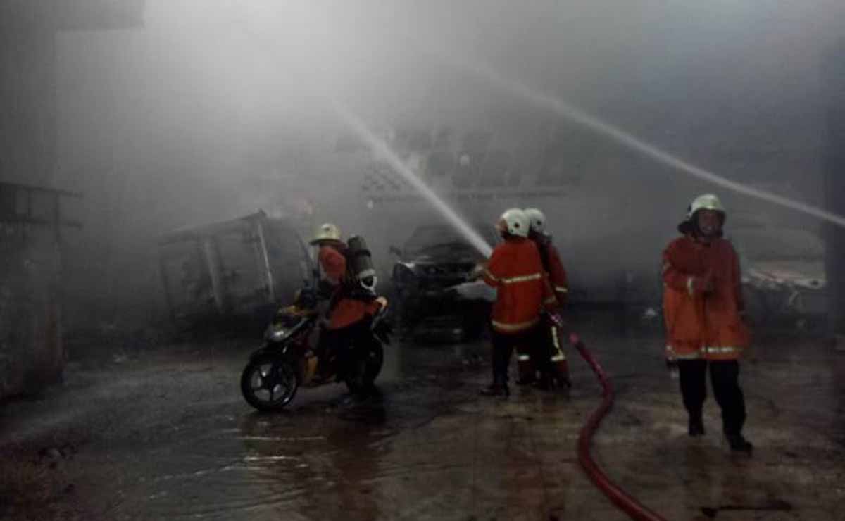 Petugas PMK berusaha memadamkan api dan mengevakusi motor serta mobil di dalam bengkel