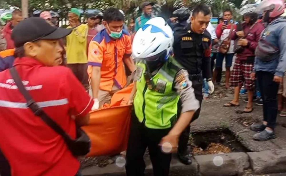 Petugas mengevakuasi jasad biker yang tewas tersenggol truk trailer di Margomulyo Surabaya