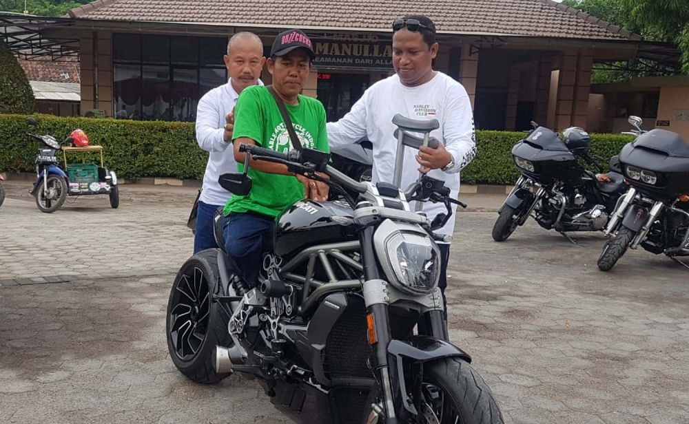 Kapolres Probolinggo Kota AKBP Ambaryadi Wijaya membantu penyandang disabilitas untuk mencoba moto gede