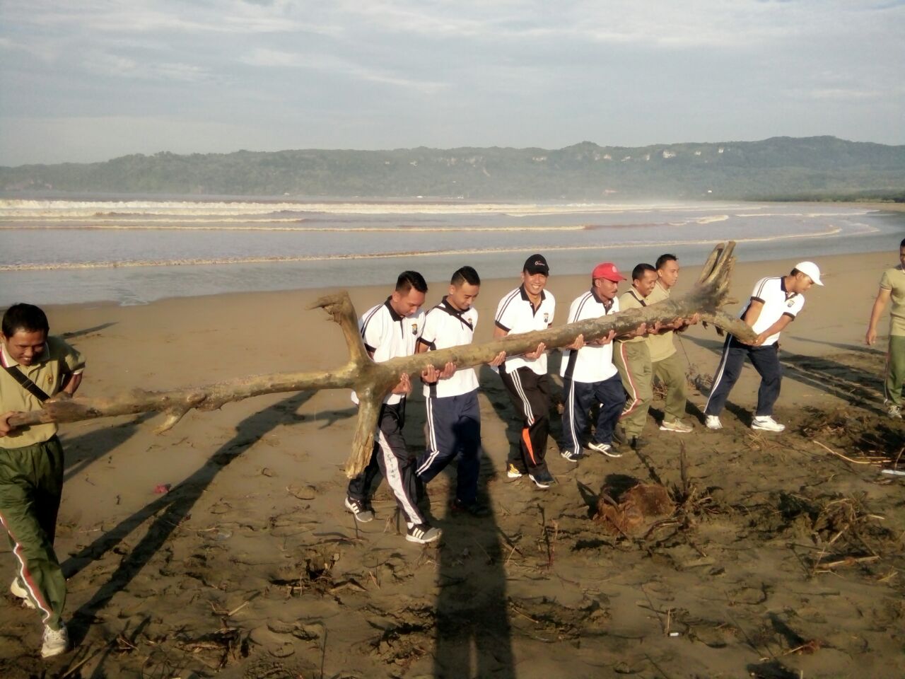 Anggota TNI dan Polri Pacitan, bersama-sama memindahkan batang kayu yang ada di  pantai pancer.