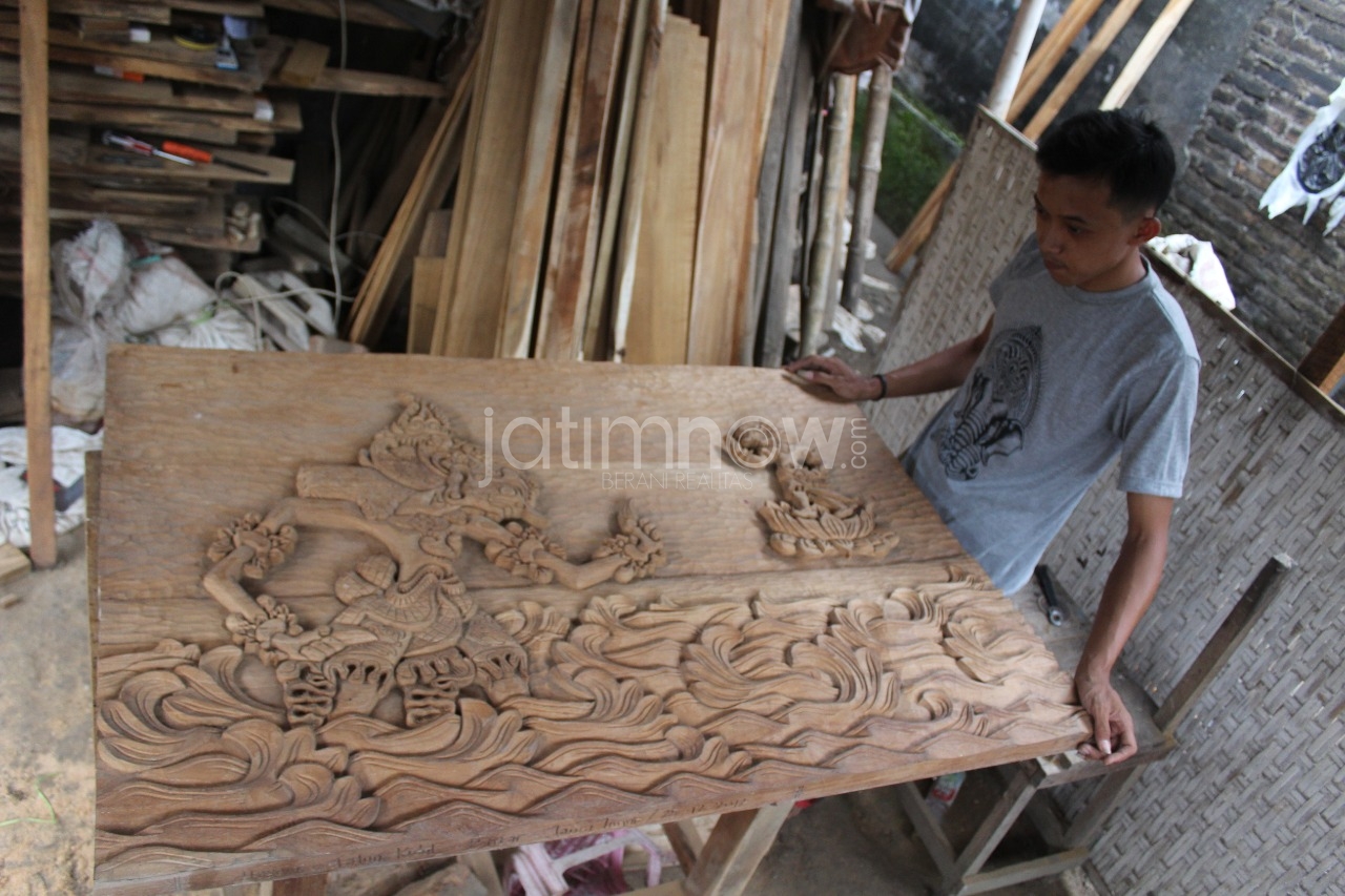 Hasam menunjukkan kayu ukirannya.