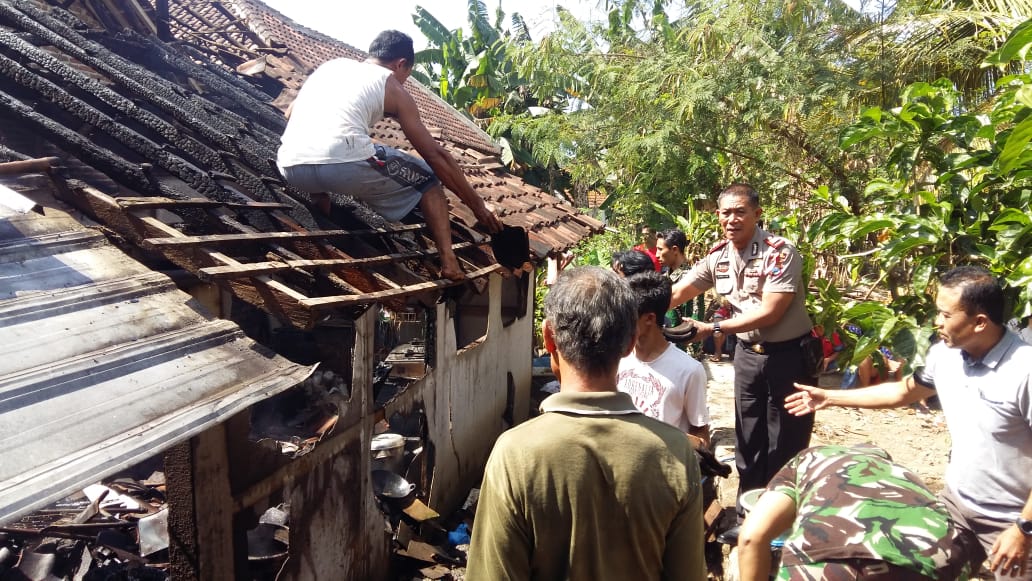 Kapolsek Kabat AKP Supriyadi dan aparat TNI dibantu warga membenahi rumah Rusmini yang terbakar.

