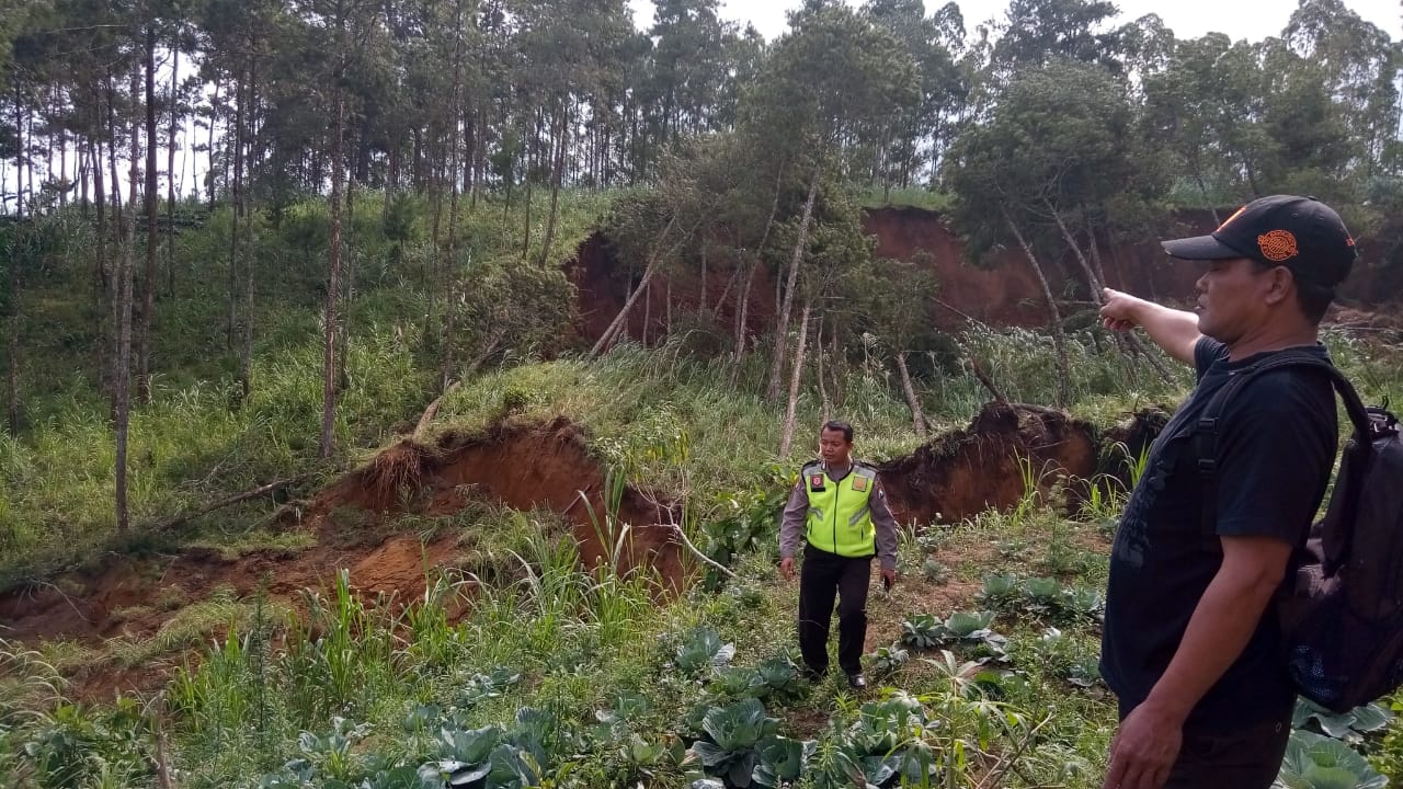 Petugas menunjukkan tanah yang longsor.