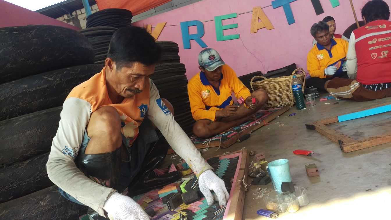 Pengrajin saat menata sandal bekas menjadi matras.