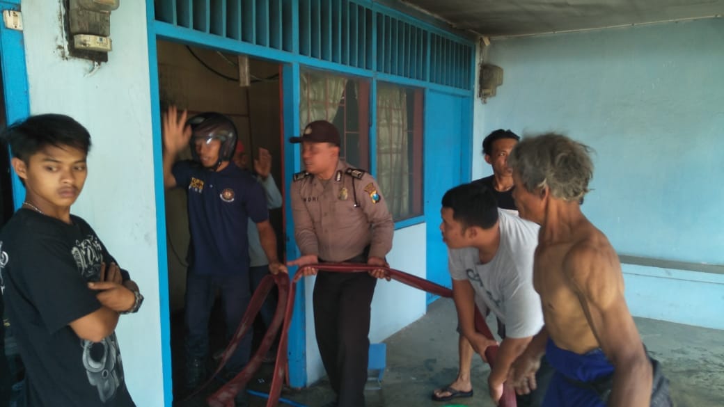 Petugas melakukan pembasahan pada gudang yang terbakar