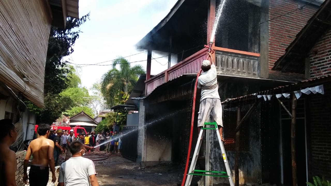 Petugas pemadam kebakaran dibantu warga saat melakukan pemadaman di TKP.