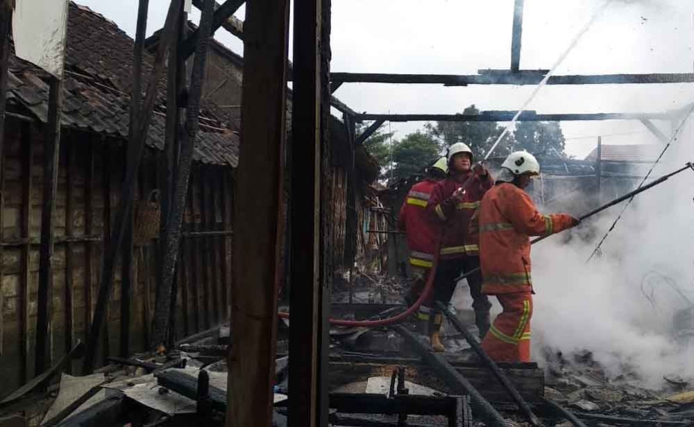 Petugas memadamkan api yang membakar rumah Supriatun