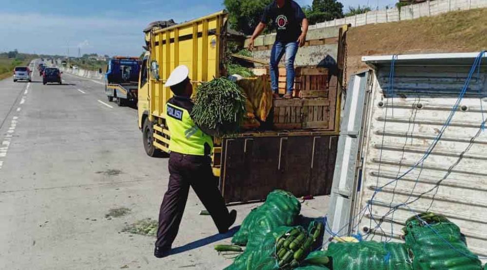 Petugas mengevakuasi muatan sayur dari pikap yang terguling di Tol Sumo